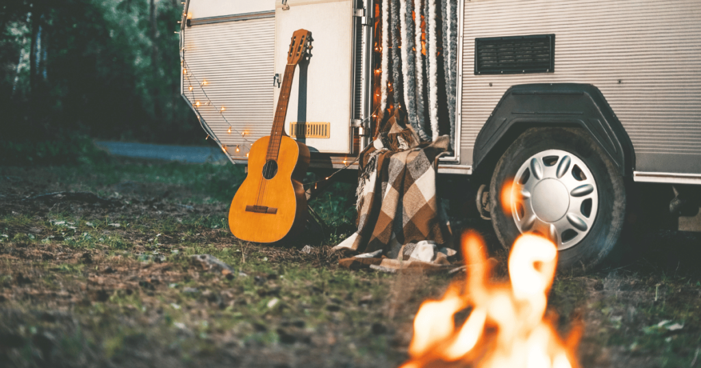 BEST CAMPING OPTION THIS IS AN IMAGE OF A CAMPER WITH A GUITAR AND A CAMPFIRE