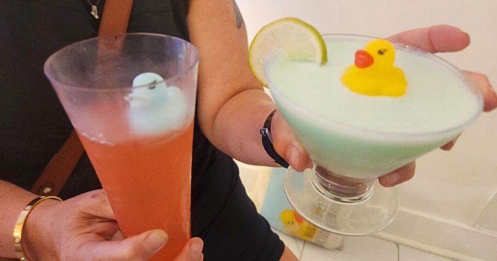 OFF THE BEATEN PATH ST. AUGUSTINE THIS IS AN IMAGE OF A WOMAN HOLDING DRINKS WITH RUBBER DUCKS