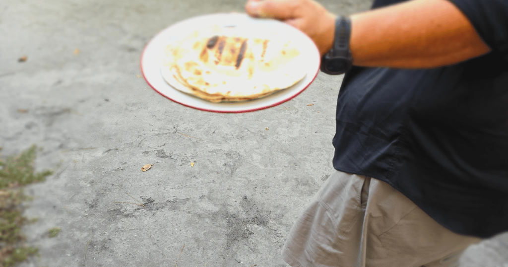 A PLATE WITH COOKED TORTILLAS FROM THE CAMPFIRE