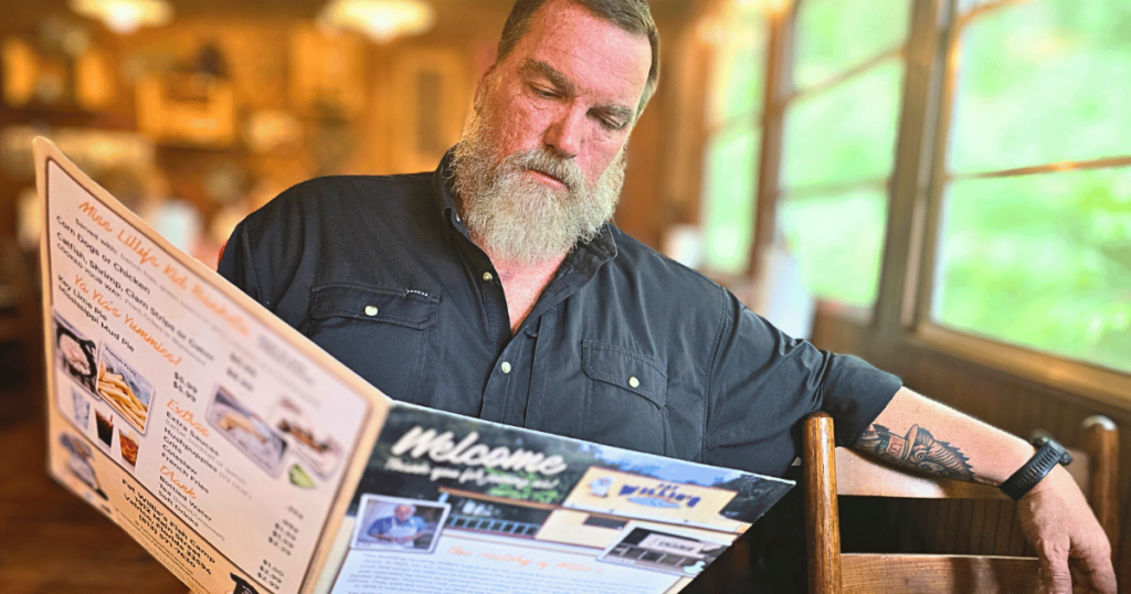 FAT WILLIE'S FISH CAMP BEST SEAFOOD DIVES IN FLORIDA MAN LOOKING AT MENU