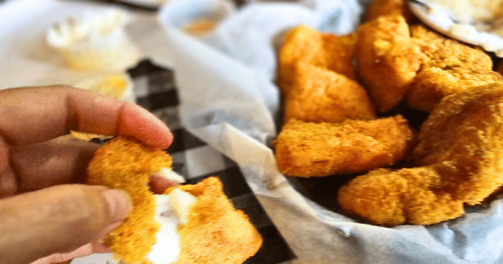 FAT WILLIE'S FISH CAMP BEST SEAFOOD DIVES IN FLORIDA HOLDING PIECE OF CATFISH