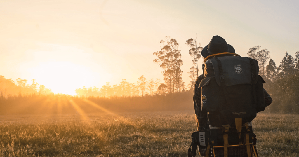 BEGINNERS GUIDE TO CAMPING THIS IS AN IMAGE OF a hiker heading out at dawn