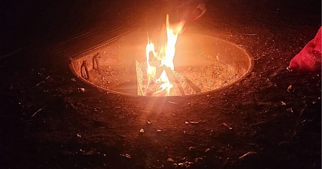 BRGINNER'S GUIDE TO CAMPING THIS IS AN IMAGE OF A CAMPFIRE IN A BARREL