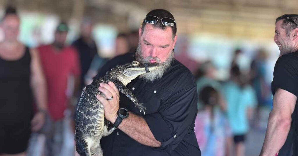 this is an image of a man kissing a baby gator in the everglades  at Wooten's
