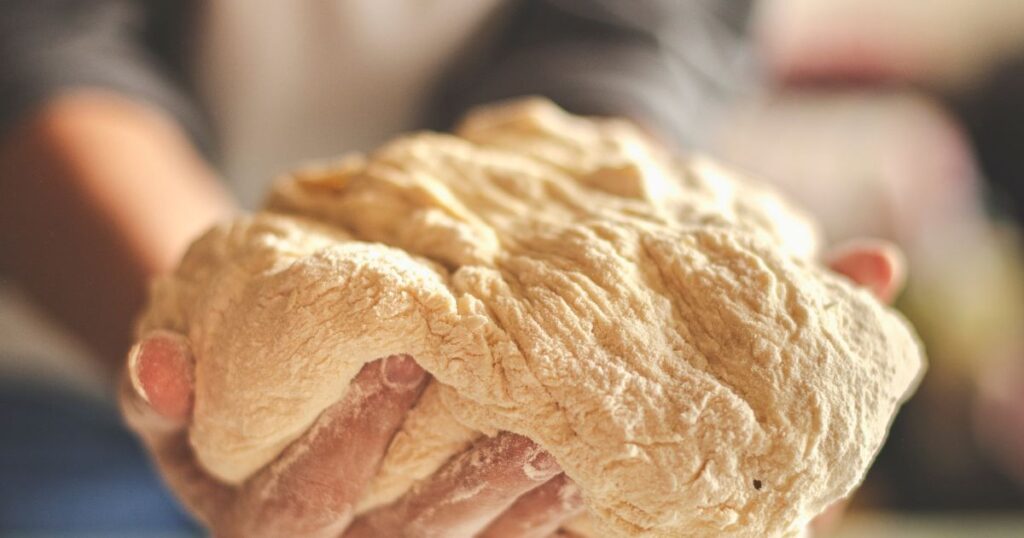this is an image of hand kneading bread dough