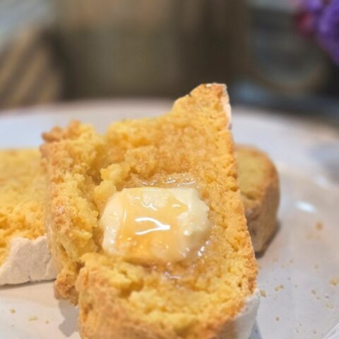 THISIS AN IMAGE OF HONEY CORNMEAL YEAST BREAD ON A PLATE WITH BUTTER