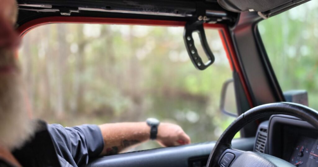 THIS IS AN IMAGE OF A MAN IN A JEEP DRIVING IN HIGHLANDS HAMMOCK STATE PARK