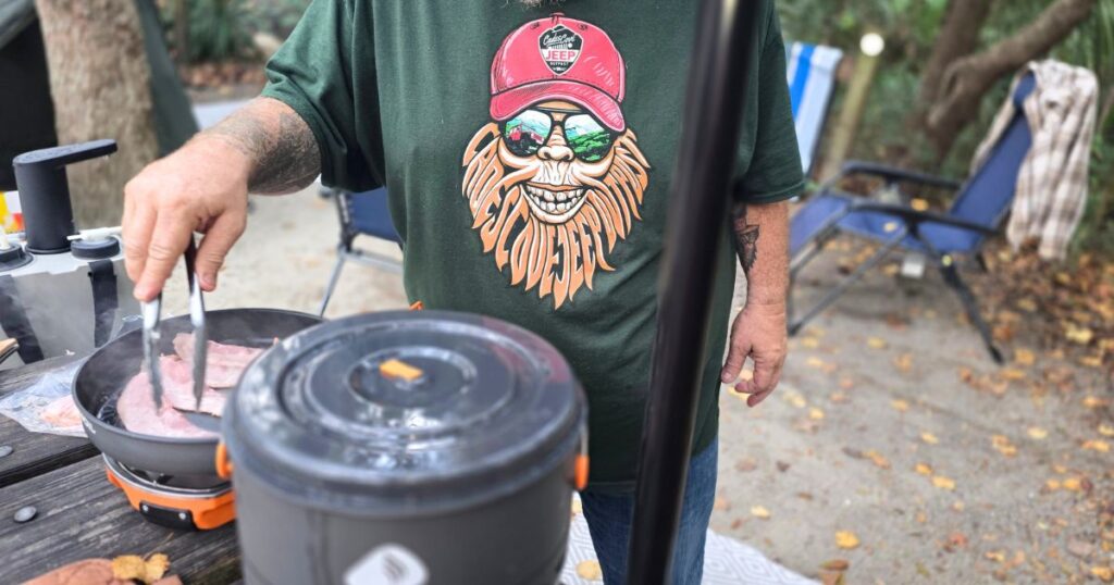 THIS IS AN IMAGE OF A MAN FRYING BACAN AT CAMP