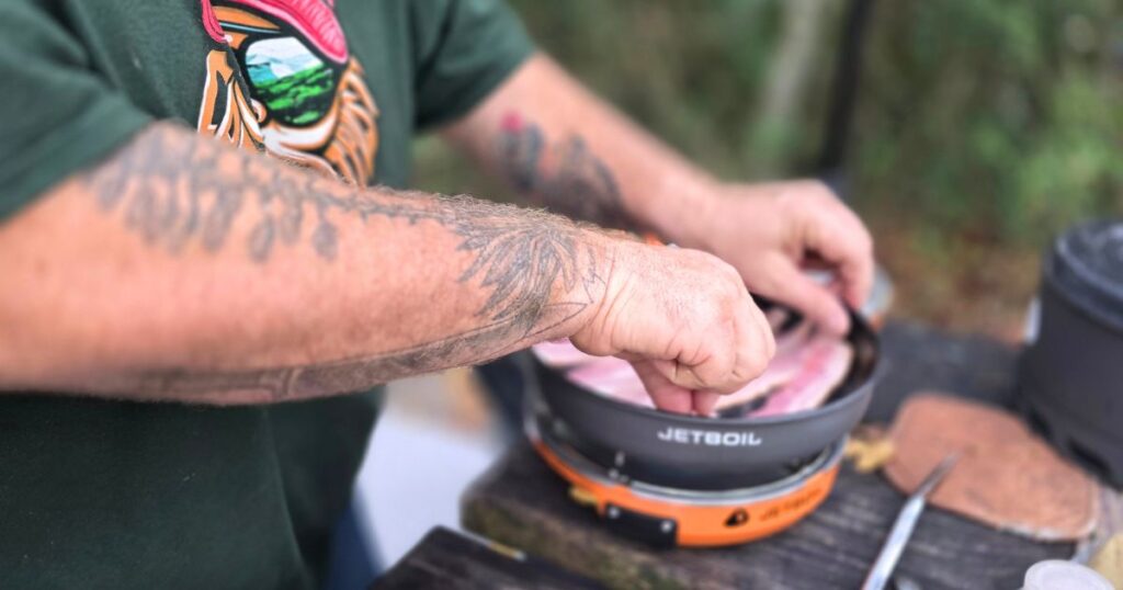 Easy Camping Breakfast Sandwich THIS IS AN IMAGE OF A MAN FRYING BACON