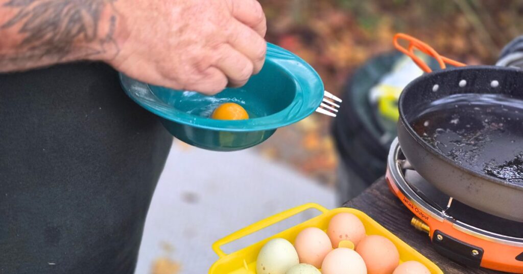 THIS IS AN IMAGE OF A MAN CRACKING EGGS INTO A BOWL