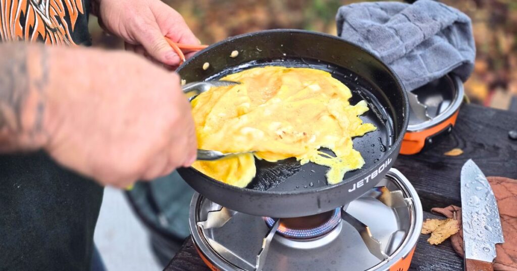 Easy Camping Breakfast Sandwich THIS IS AN IMAGE OF A MAN SCRAMBLING EGGS AT CAMP