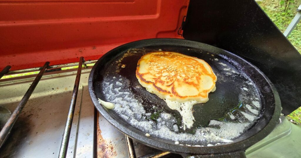 THIS IS AN IMAGE OF THE CAMP CHEF EVERST 2X WITH A PAN COOKING A PANCAKE