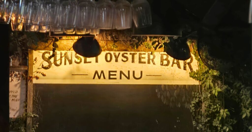IMAGE OF THE OYSTER BAR SIGN AT NIGHT AT CAPS ON THE WATER