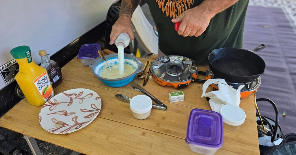 THE BEST CAR CAMPING PORTABLE KITCHEN AND SETUP THIS IS AN IMAGE OF A MAN COOKING AT CAMP ON A BAMBOO TABLE