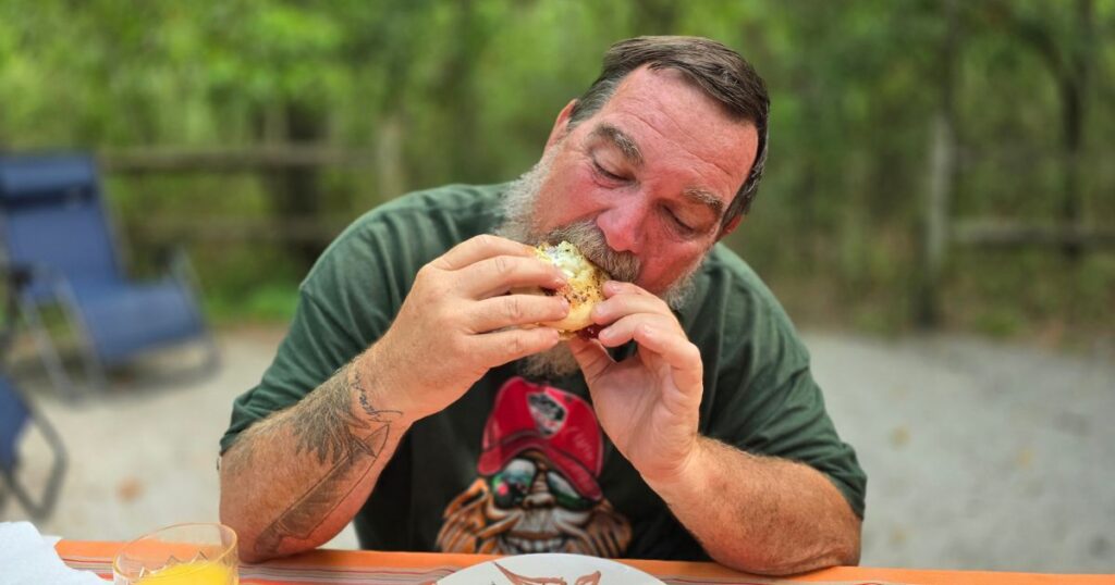 THIS IS AN IMAGE OF A MAN EATING BREAKFAST AT CAMP