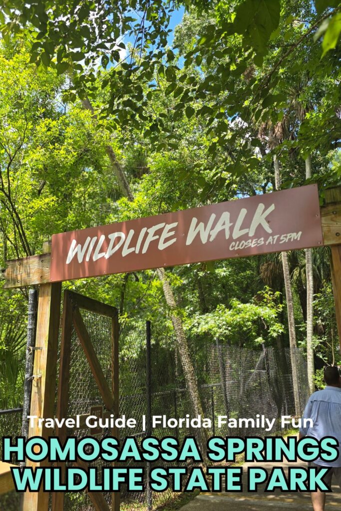 Wildlife walk sign at Homosassa Springs Wildlife State Park in Florida with lush green trees.