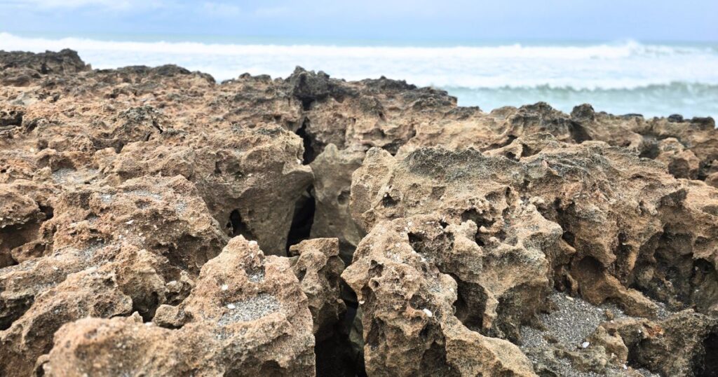 Rugged volcanic rocks on a Hawaii coastline with ocean waves in the background.