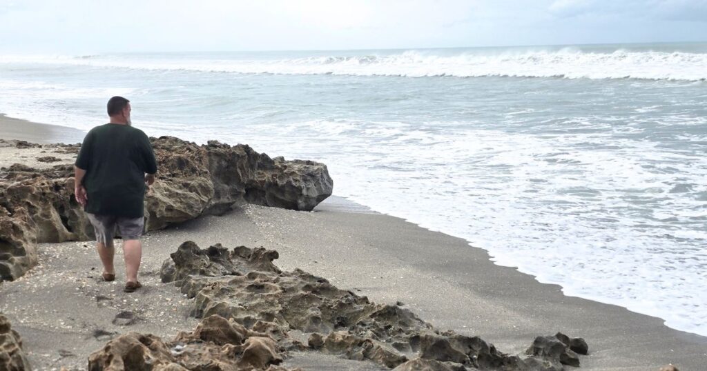 Seaside walk along rocky beach with ocean waves, beach lover exploring coastal scenery.