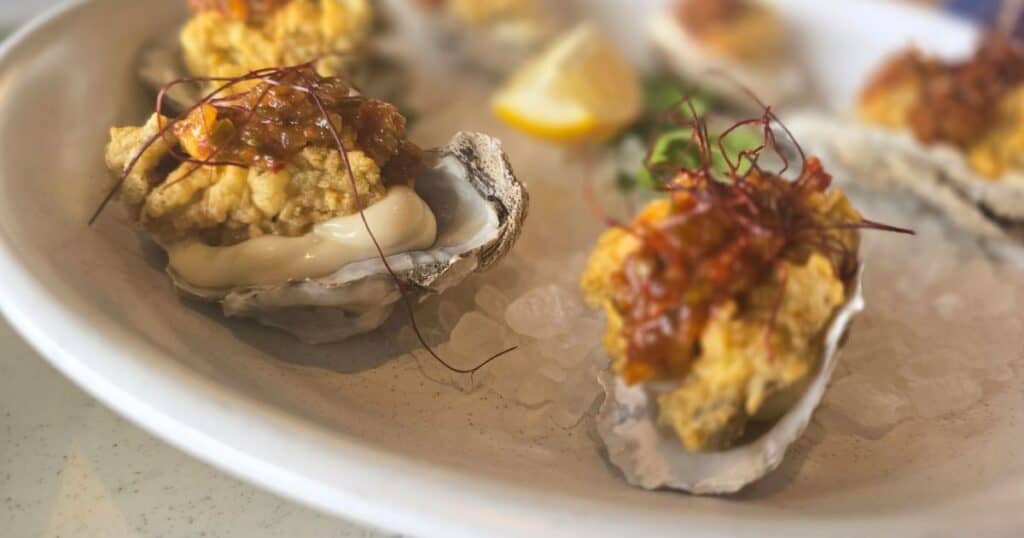 Fresh oysters topped with flavorful seafood stuffing and garnished with herbs and lemon wedges.