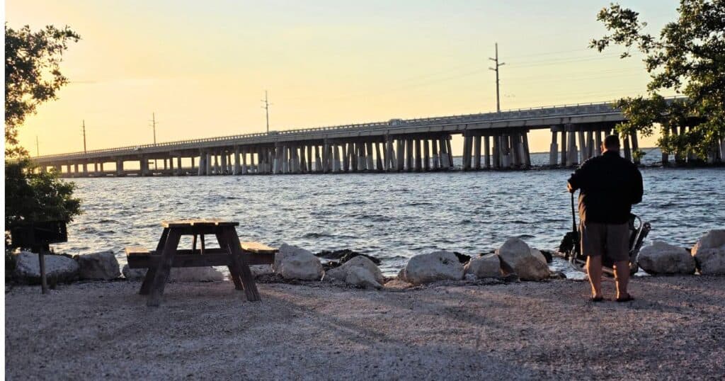 Sunset over pier with fisherman at the beach, scenic ocean view, coastal travel, outdoor activity, The Wandering Hulasquatch.