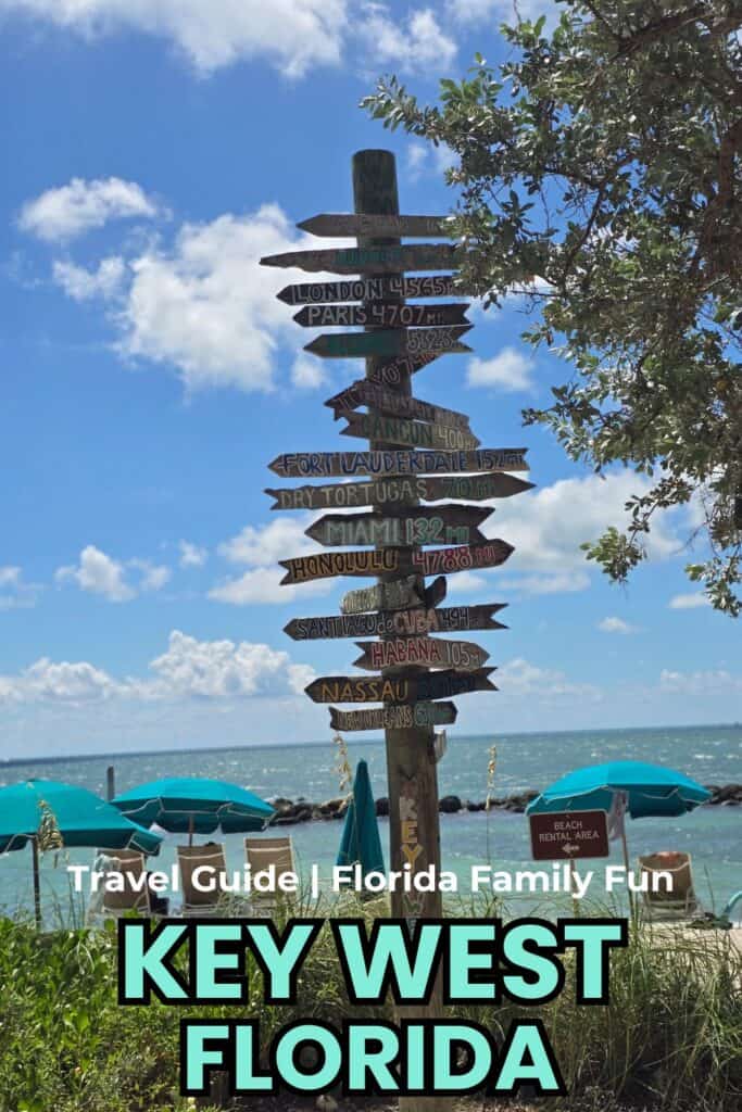 Florida beach signpost with multiple travel destinations in Key West, ocean view, blue sky, and beach umbrellas, promoting family fun and travel.