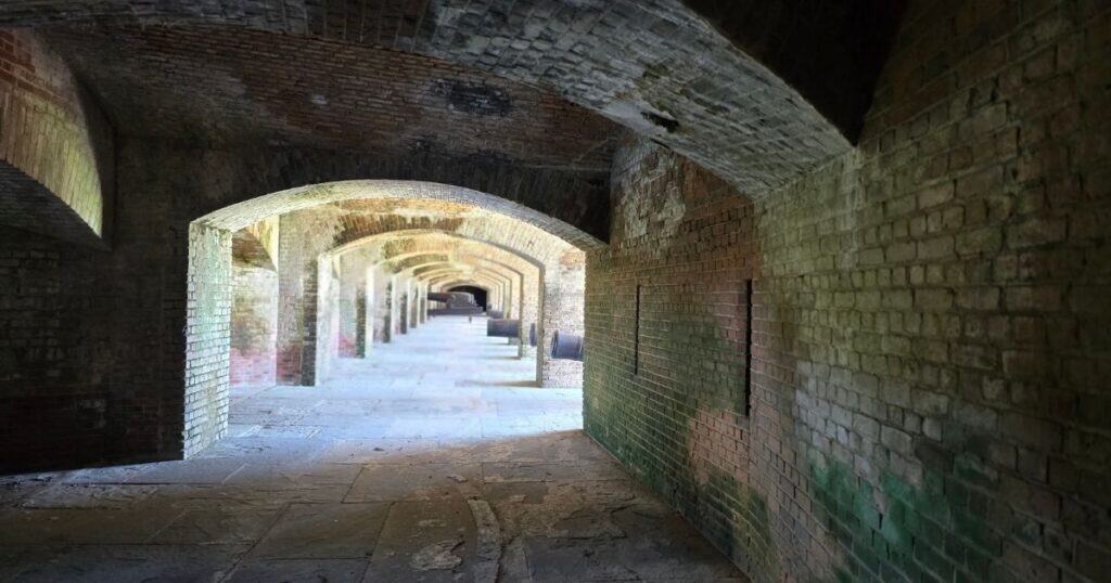 Ancient brick tunnel with arched ceilings and moss-covered walls, historic architecture and underground passageways.