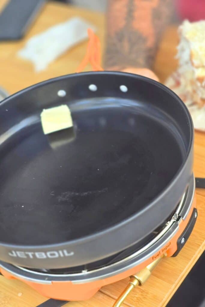 EASY CAMPING BREAKFAST RECIPE BUTTER IN A SKILLET ON A CAMP STOVE