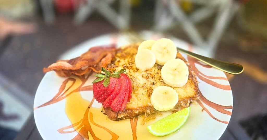 PINA COLADA FRENCH TOAST EASY CAMPING BREAKFAST RECIPE FRENCH TOAST ON A PLATE WITH FRESH FRUIT